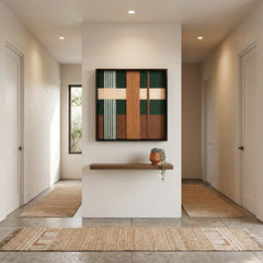 Square textured fiber art creating a sophisticated focal point in a minimalist hallway foyer with light oak architectural accents.