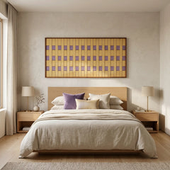 Framed textured fiber wall art styled as a headboard focal point in a serene bedroom with cream linens and lavender accents.