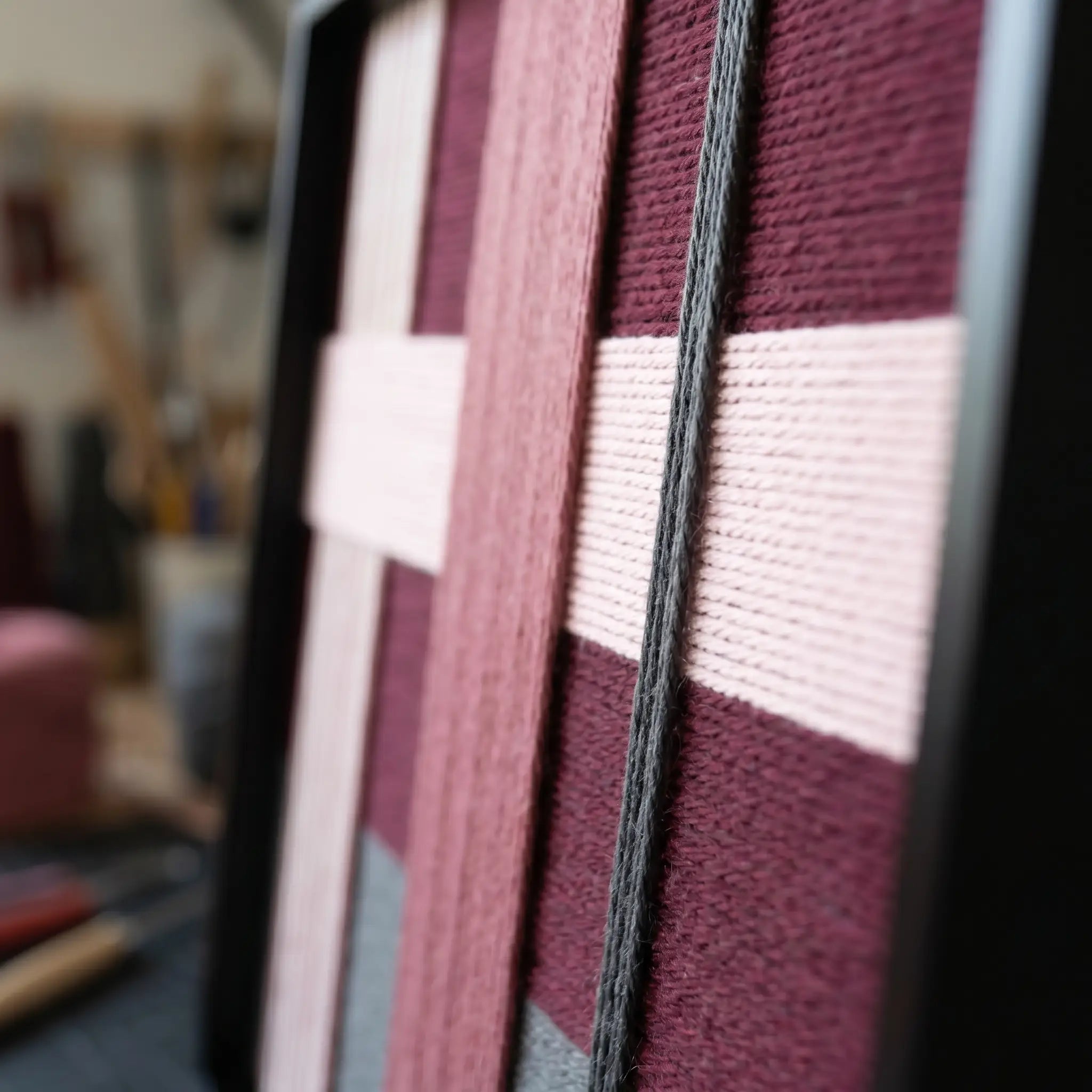 An angled close-up view of the framed fiber wall art showcasing the structural multi-directional layering and dimensional depth of the wool yarn.