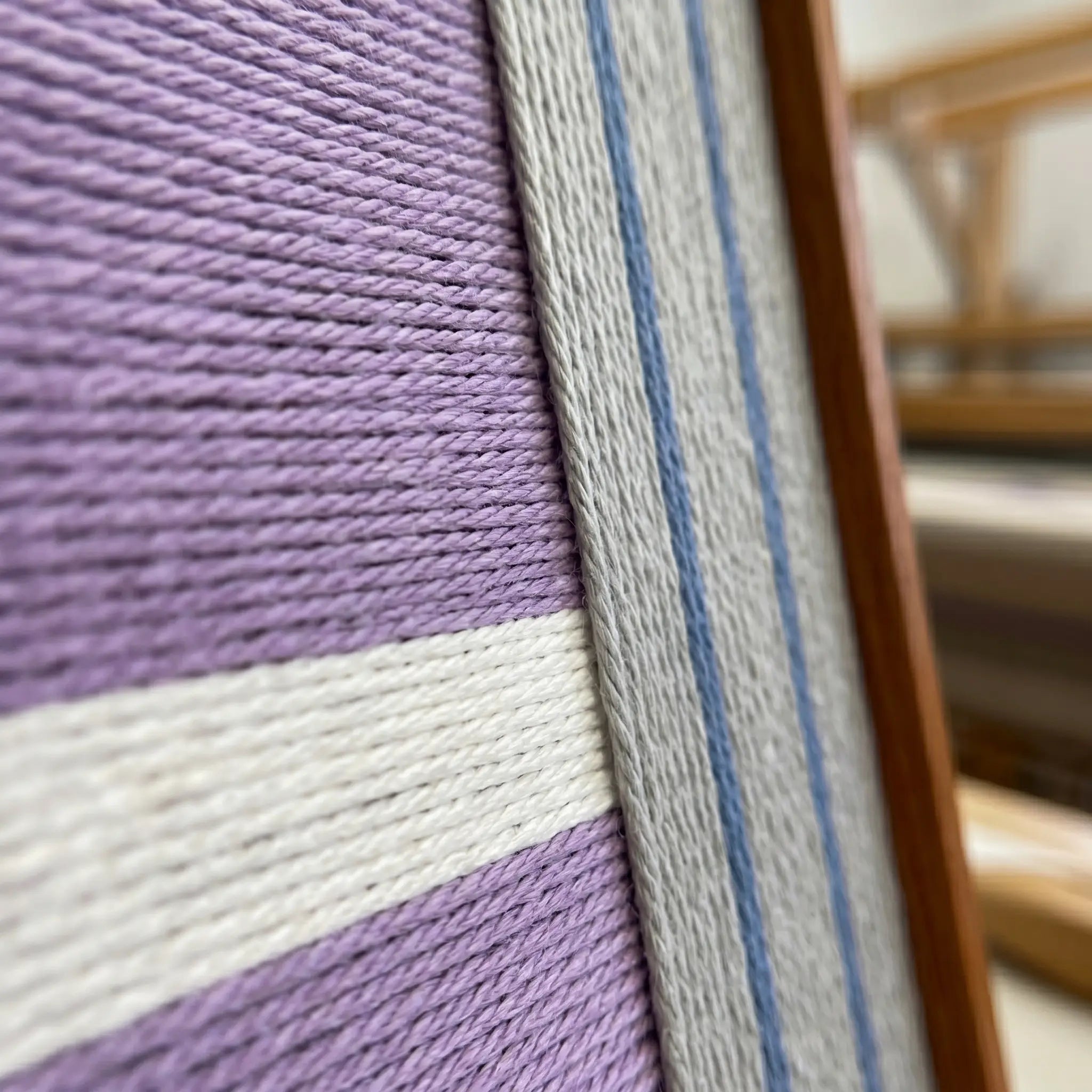 Close-up side view of the framed wool art highlighting the dense purple fibers and the sleek finish of the wooden frame.
