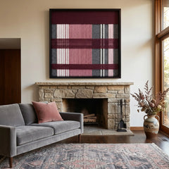Beautiful framed hand-woven textile wall art styled elegantly above a rustic stone fireplace mantel in a cozy living room featuring a grey sofa.