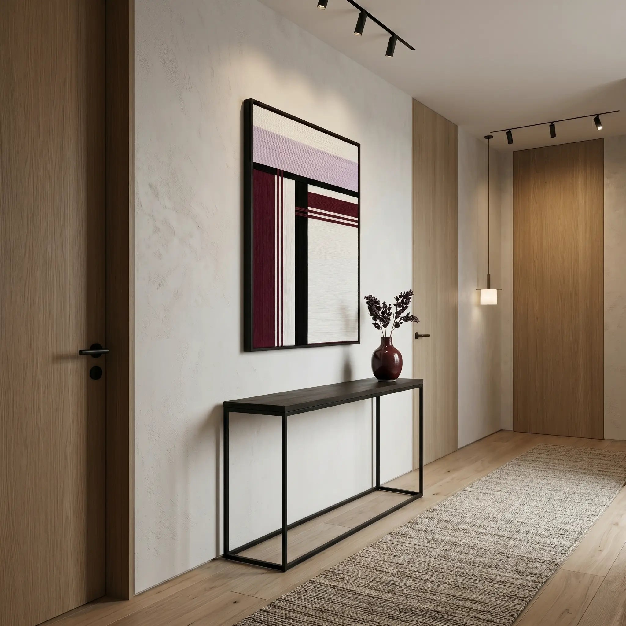 Sophisticated framed wool wall art displayed in a minimalist hallway above a black metal console table.