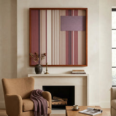 Large square Midnight Plum hand-woven wall art hanging elegantly above a classic white fireplace mantel next to a cozy caramel armchair in a living room.