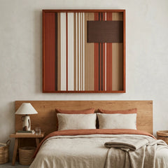 Beautiful square framed hand-woven textile wall art styled elegantly above a wooden bed frame with matching rust and cream bedding in a cozy bedroom.