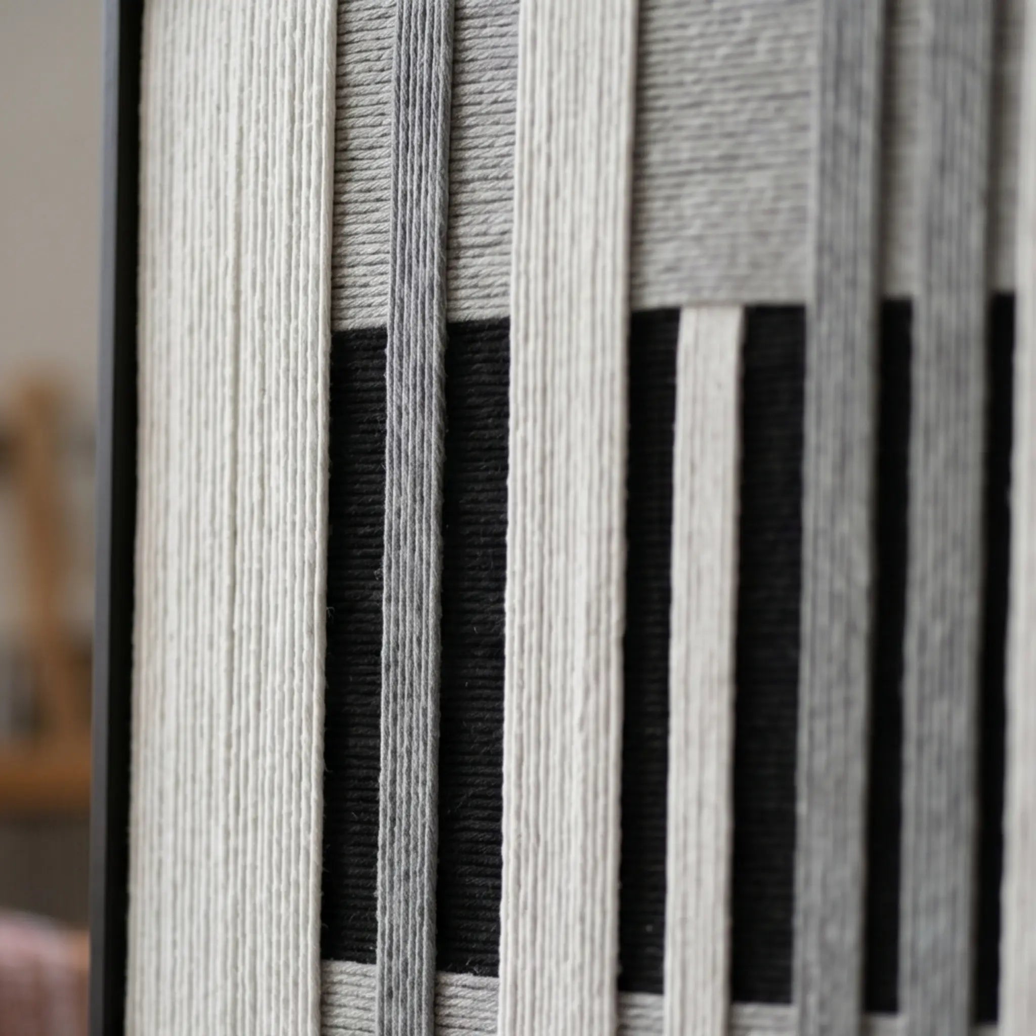 Detailed macro close-up of the Monochrome Tempo hand-woven wool tapestry highlighting the thick black, white, and grey textured yarn.