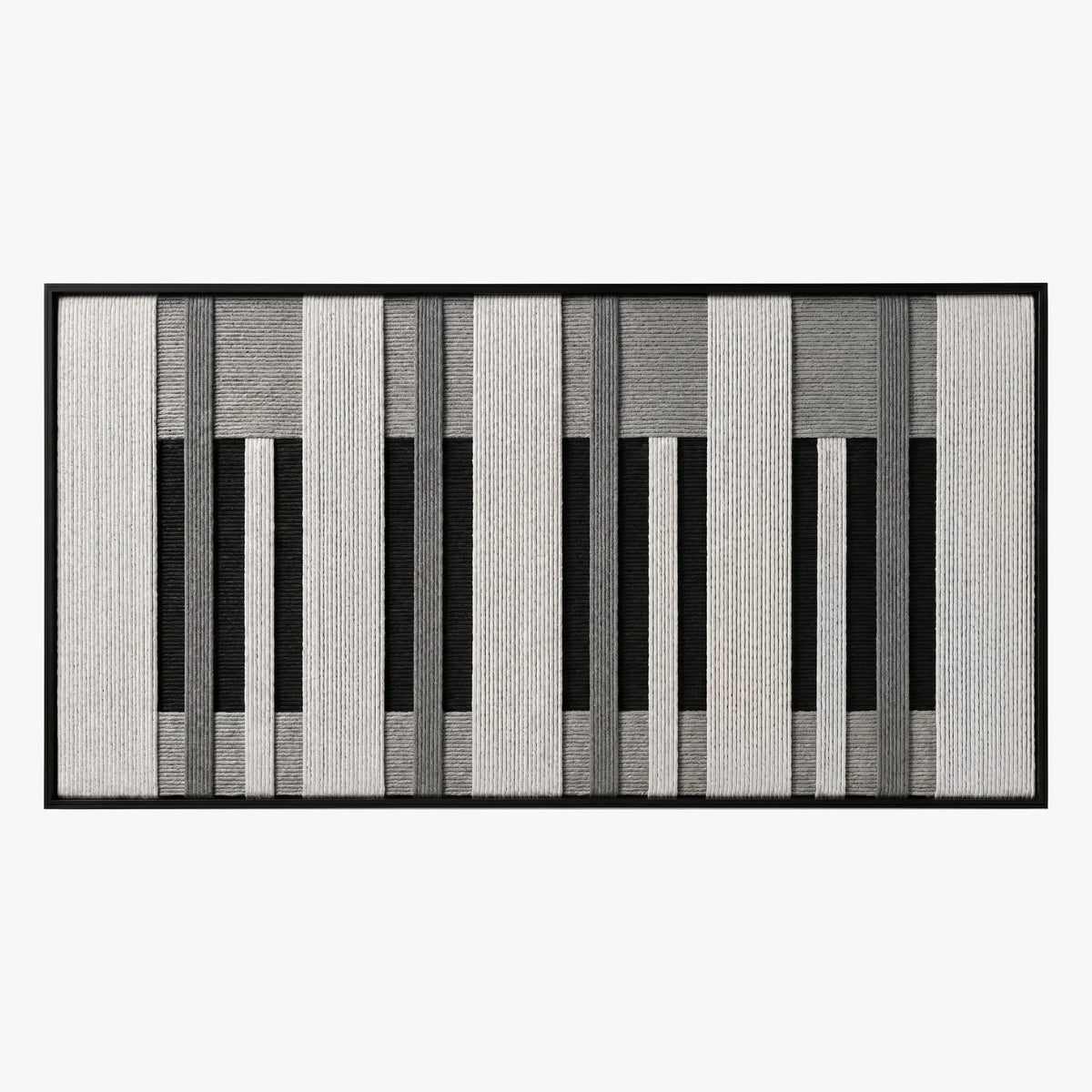 Frontal studio shot of the Monochrome Tempo hand-woven wool tapestry featuring a black, white, and grey piano key geometric pattern in a black frame.