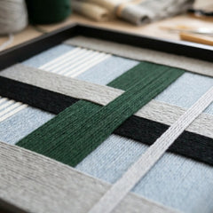 Extreme close-up of Moonlight Glade hand-woven wool art showing the intricate forest green, navy, and light blue yarn textures in a black frame.