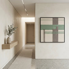 Square pastel green and grey textured wool art creating a serene focal point in a bright minimalist hallway.