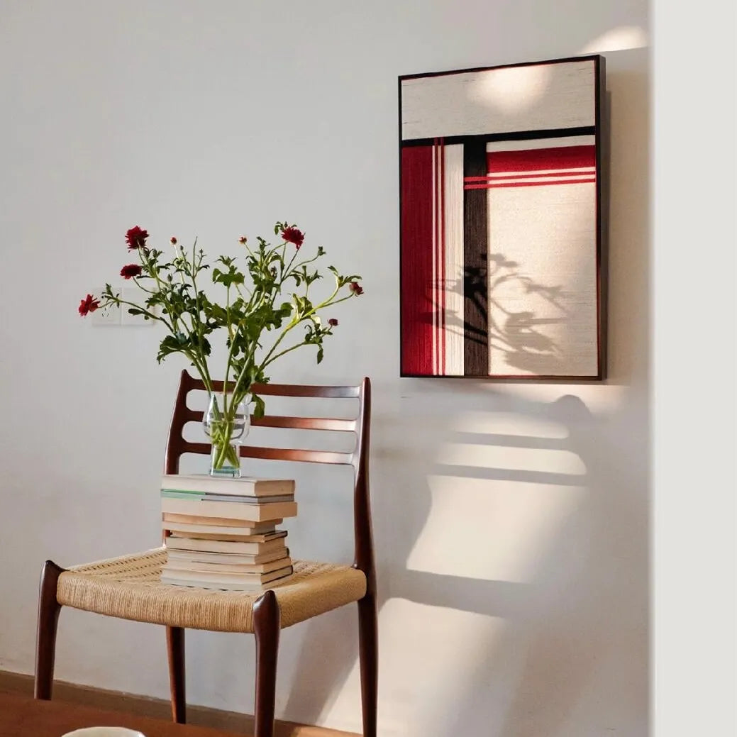“Napoli” yarn wall art reflected in a mirror to showcase the full red and black stripe design and sleek frame
