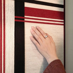Close-up of “Napoli” yarn wall art capturing the tactile looped wool and the contrast between red and black stripe fibers
