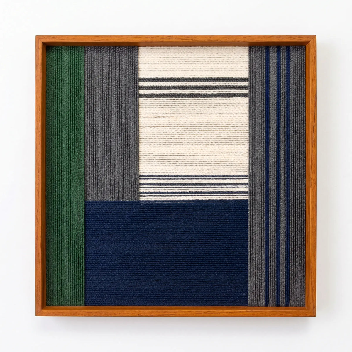Professional studio shot of the Needle and Ink hand-woven wool wall art in an oak frame against a clean white background.