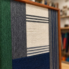 An angled view of the framed wool art highlighting the high-value texture of the hand-wrapped yarn and structural geometric patterns.