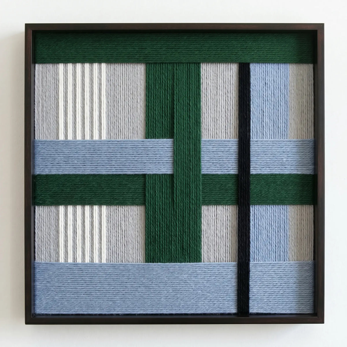 Frontal studio shot of the "Polar Forest" hand-woven wool wall art in a square black frame against a clean white background.