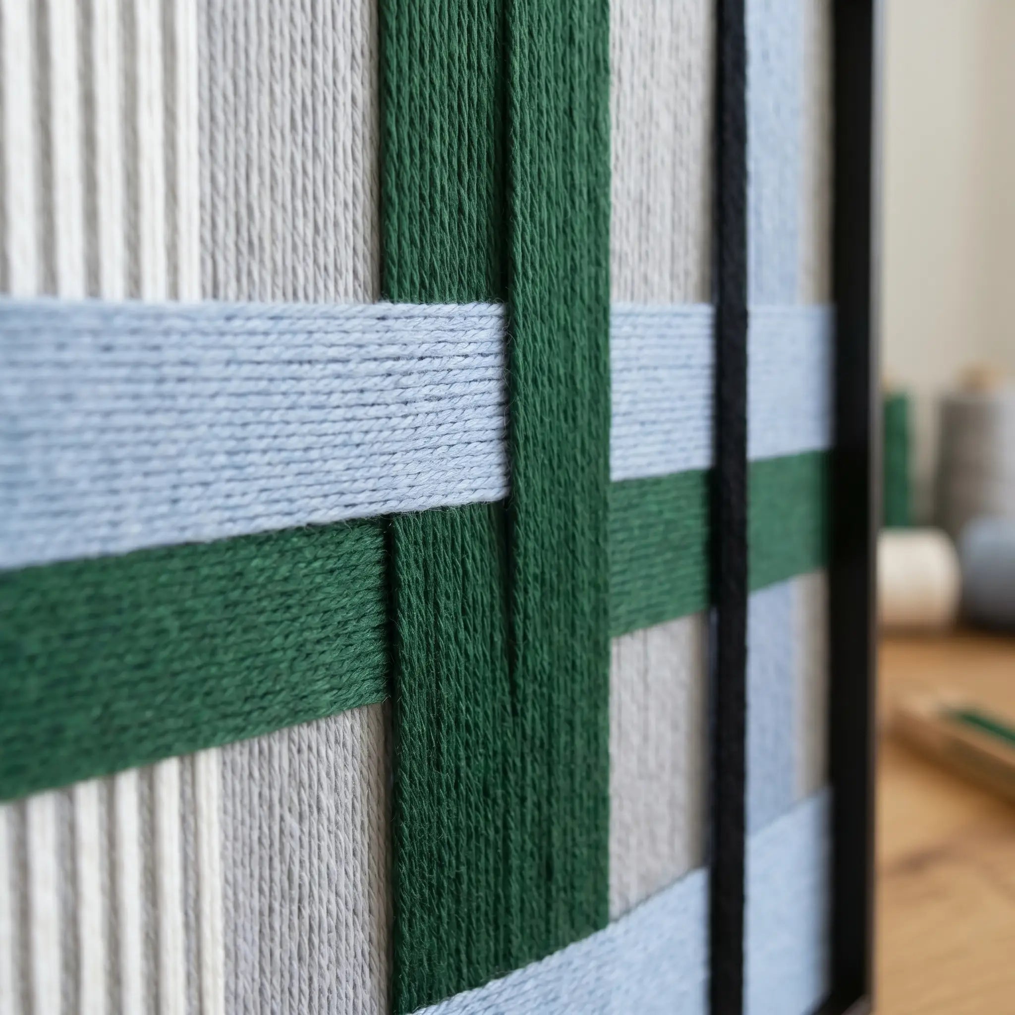 Close-up of the "Polar Forest" wall art highlighting the intricate forest green and light blue hand-wrapped yarn textures and black frame.