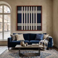Large square Polar Meridian hand-woven wall art hanging elegantly above a plush navy blue sofa in a bright, modern living room.