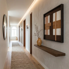 Vertical perspective of a modern hallway featuring the earth-toned wool tapestry hanging above a minimalist floating wood shelf.