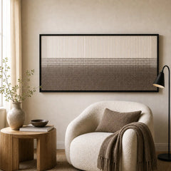Framed hand-woven wool tapestry styled in a cozy reading nook, positioned perfectly next to a white curved armchair.
