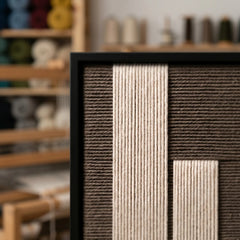 Close-up of the Silent Stelae framed wall art showing the precision of the hand-woven cream yarn set within a modern black frame.