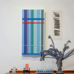 Summer Story yarn wall art styled on a desk beside a lamp and notebook, emphasizing its balanced horizontal stripe design
