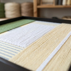 Close-up of the Sun-Baked wool art in a studio, highlighting the intricate hand-wrapped yarn textures and precise geometric layering.
