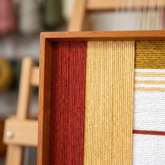 Close-up shot of the oak wood frame corner highlighting the rich, tactile hand-woven wool textures and precise layered winding technique.