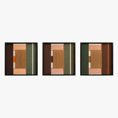 Frontal studio shot of the Sylvan Glow triptych, showcasing three matching square hand-woven wall art pieces with green, tan, and rust geometric designs in black frames.