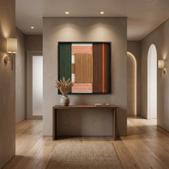 Square forest-toned textured fiber art hanging in a minimalist home foyer above a simple wooden console table.