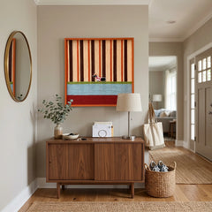 Large square Tangerine Stripe Pup Venture textile wall art featuring orange stripes, a blue color block, and a small dog detail, hanging above a mid-century modern wooden cabinet in a bright entryway.