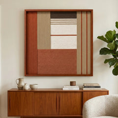 Striking square hand-woven wool tapestry positioned perfectly above a classic wooden sideboard next to a large potted plant in a sunlit living space.