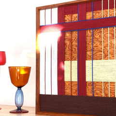 Artistic close-up of the woven wool tapestry with a light flare, highlighting the intricate texture and vibrant red and orange color palette.