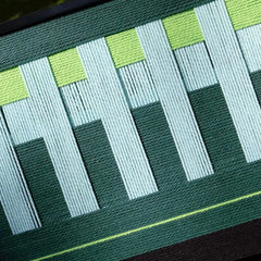 Macro shot of Velvet Vine yarn wall art emphasizing tight stitching and color depth of green and white yarns
