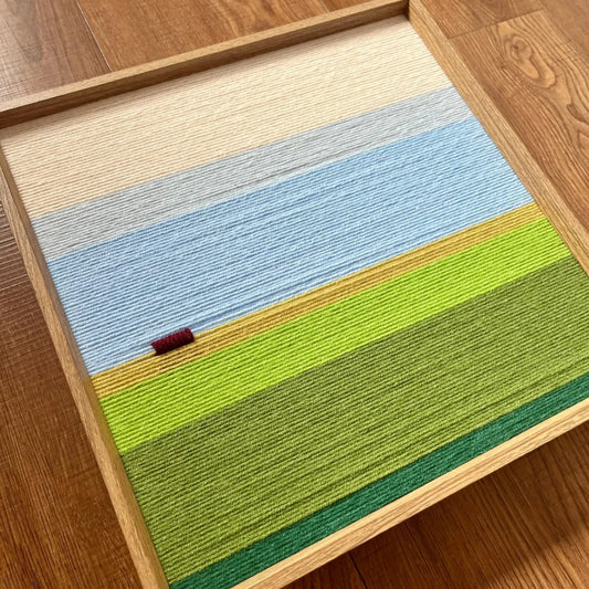 Close-up corner detail of the hand-woven wool tapestry showing textured blue and green fields in a wooden frame.
